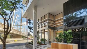 Un edificio moderno con mostrador de recepción, ventanas amplias y una escalera que lleva a un nivel superior.