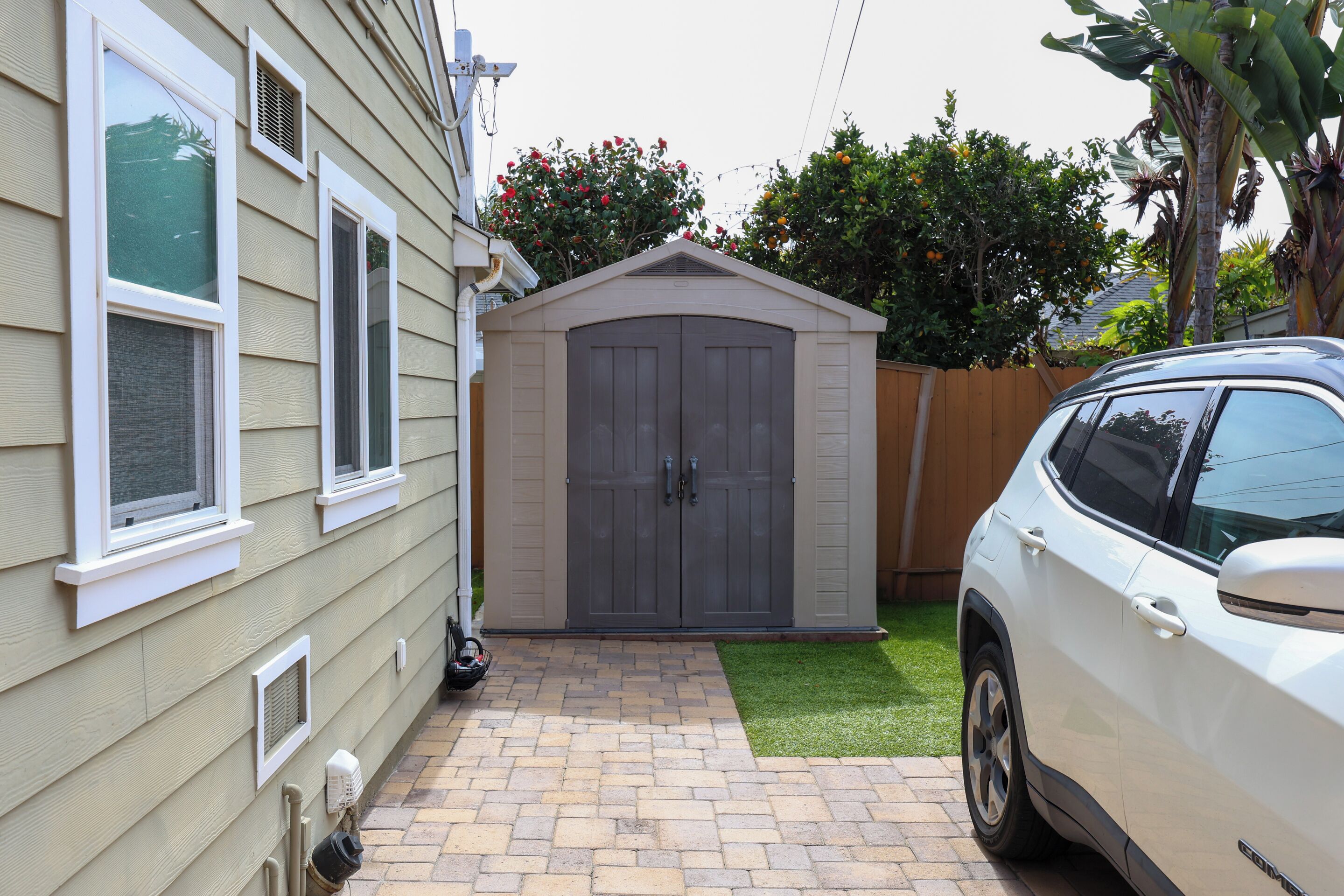 Une maison avec un garage, une allée pavée et une voiture garée dans l’allée.