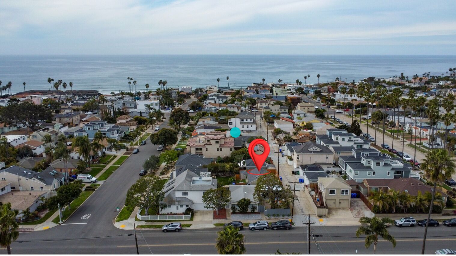 A residential area with houses, streets, and a view of the ocean.