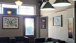 Une salle de billard équipée d’une table de billard, de deux fauteuils et de tableaux encadrés aux murs.