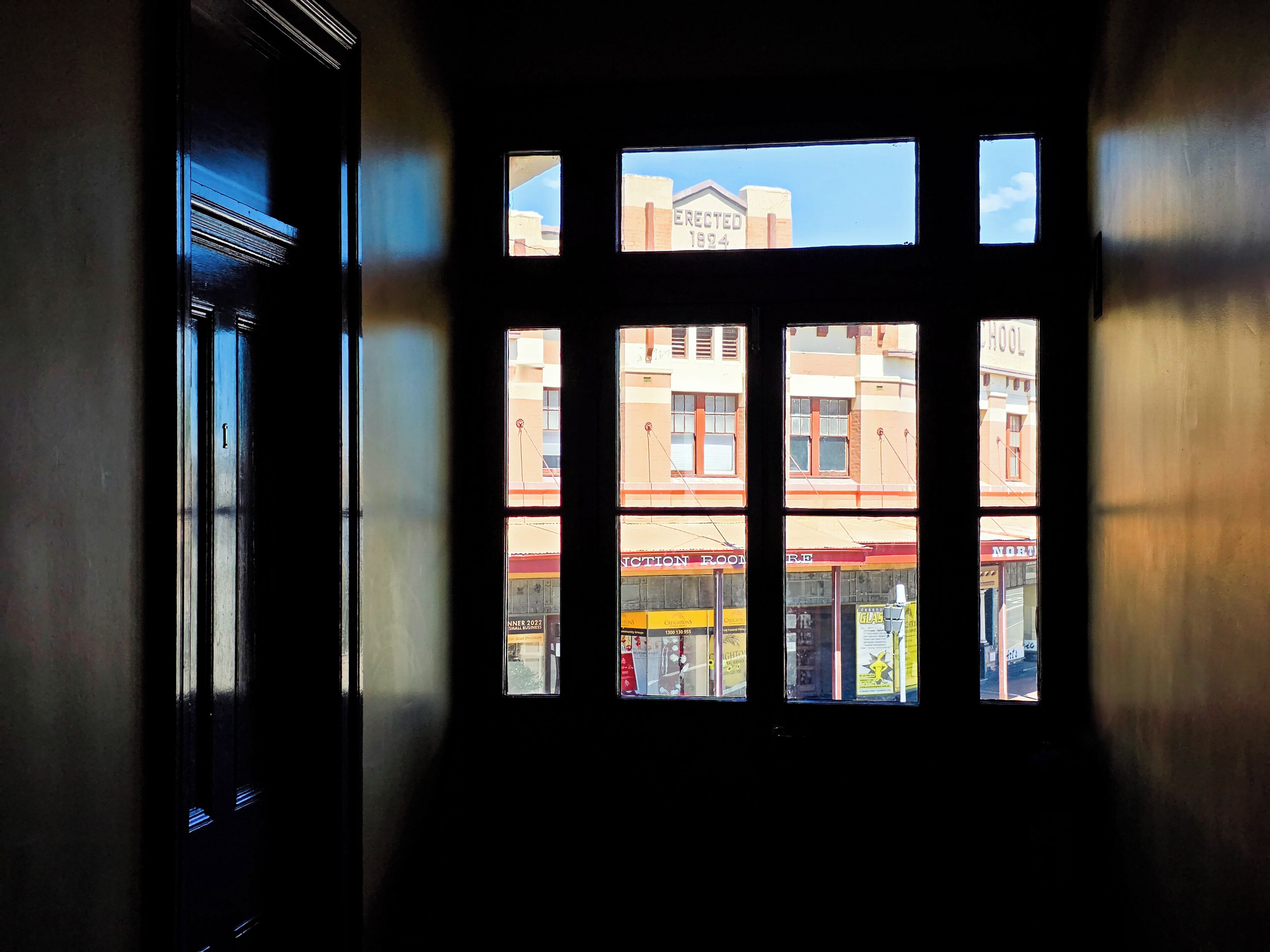 A window with multiple panes, each showing different buildings and signs, including a school and a store.
