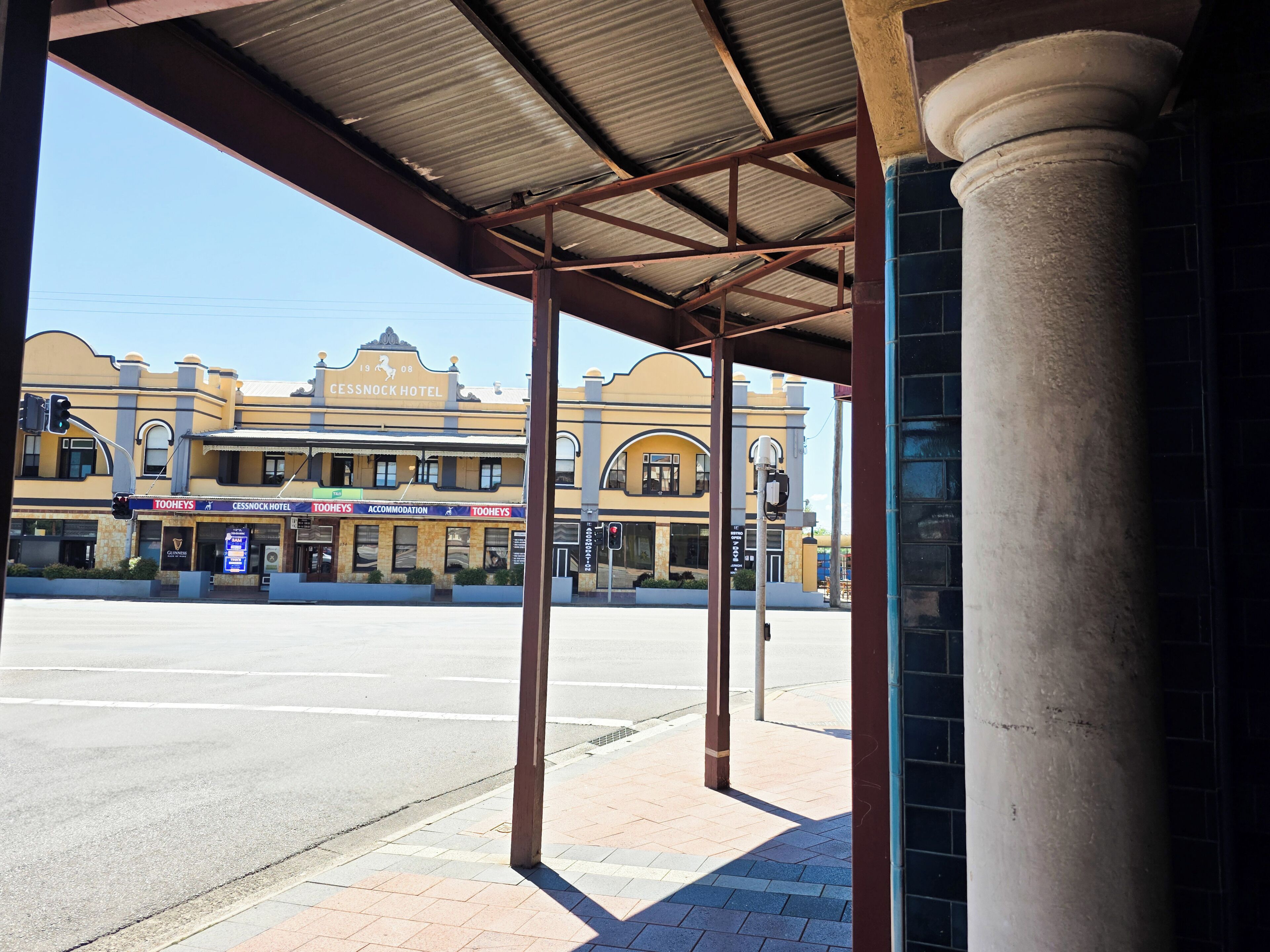 A hotel with a covered entrance, a street view, and a clear sky.