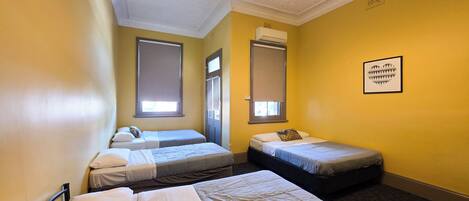A room with three beds, a ceiling light fixture, and an air conditioning unit.