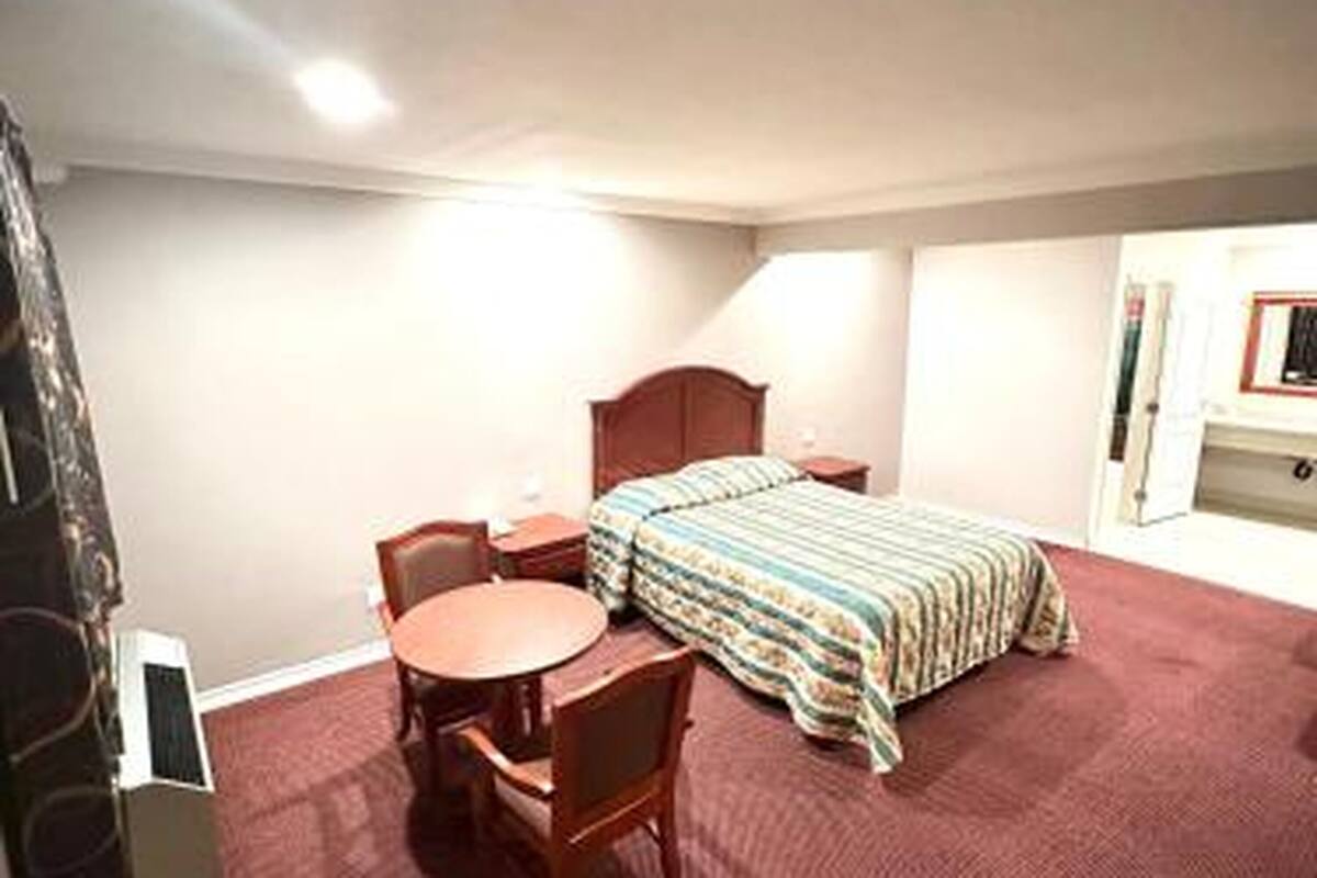 Una camera d'albergo con un letto, un tavolino rotondo e una sedia.