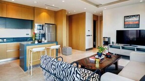 Eine moderne Küche mit Holzschränken, einer zentralen Kochinsel und einem Essbereich mit gepunkteter Couch und Couchtisch.