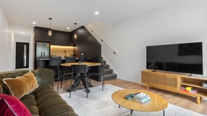 Una sala de estar moderna con un sofá, una mesa de centro, un televisor y un comedor con sillas y una mesa.