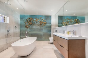 Un bagno moderno con una vasca freestanding, un box doccia in vetro e un ampio specchio sopra il mobile lavabo.