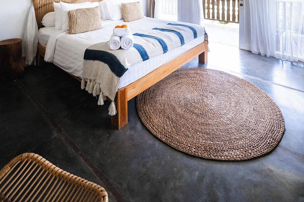 Ein Schlafzimmer mit einem hölzernen Bett, einem gewebten Teppich und einem Baldachinbett.