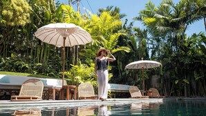 Una piscina con lettini e ombrelloni, circondata da rigogliosa vegetazione.