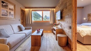 A room with a wooden wall, a sofa, a coffee table, a TV, and a bed. - Beautiful apartment for 6 people with WIFI, terrace and pets allowed (Zinal)