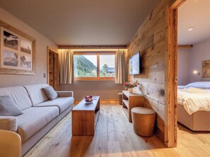 Ein Zimmer mit Holzwand, einer Couch, einem Couchtisch, einem Fernseher und einem Bett.