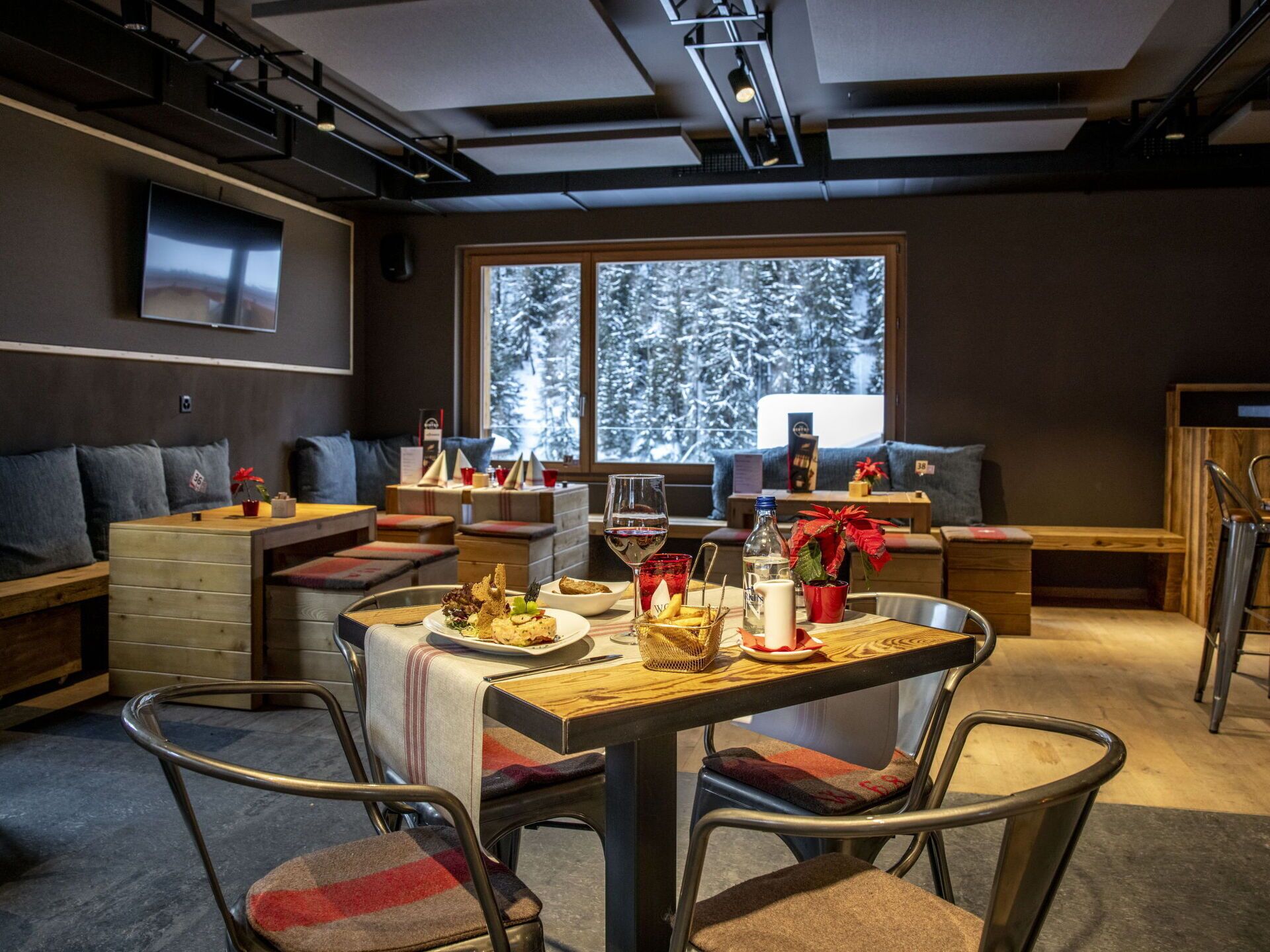 Un comedor moderno con una mesa de madera, sillas de metal y un amplio ventanal con vista nevada.