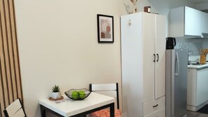 Una cocina compacta con armarios blancos, un refrigerador blanco y una mesa de comedor con sillas.