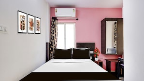 Una habitación de hotel con cama, escritorio, espejo y aire acondicionado.