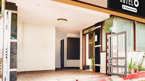 Entrada de un hotel con alfombra a rayas, una escalera y un letrero que dice 'HOTEL Company-Serviced'.