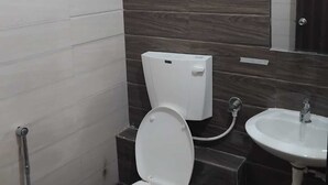 A bathroom with a toilet, bidet, and sink. - Kiwi Inn Hotel Palda (Indore)
