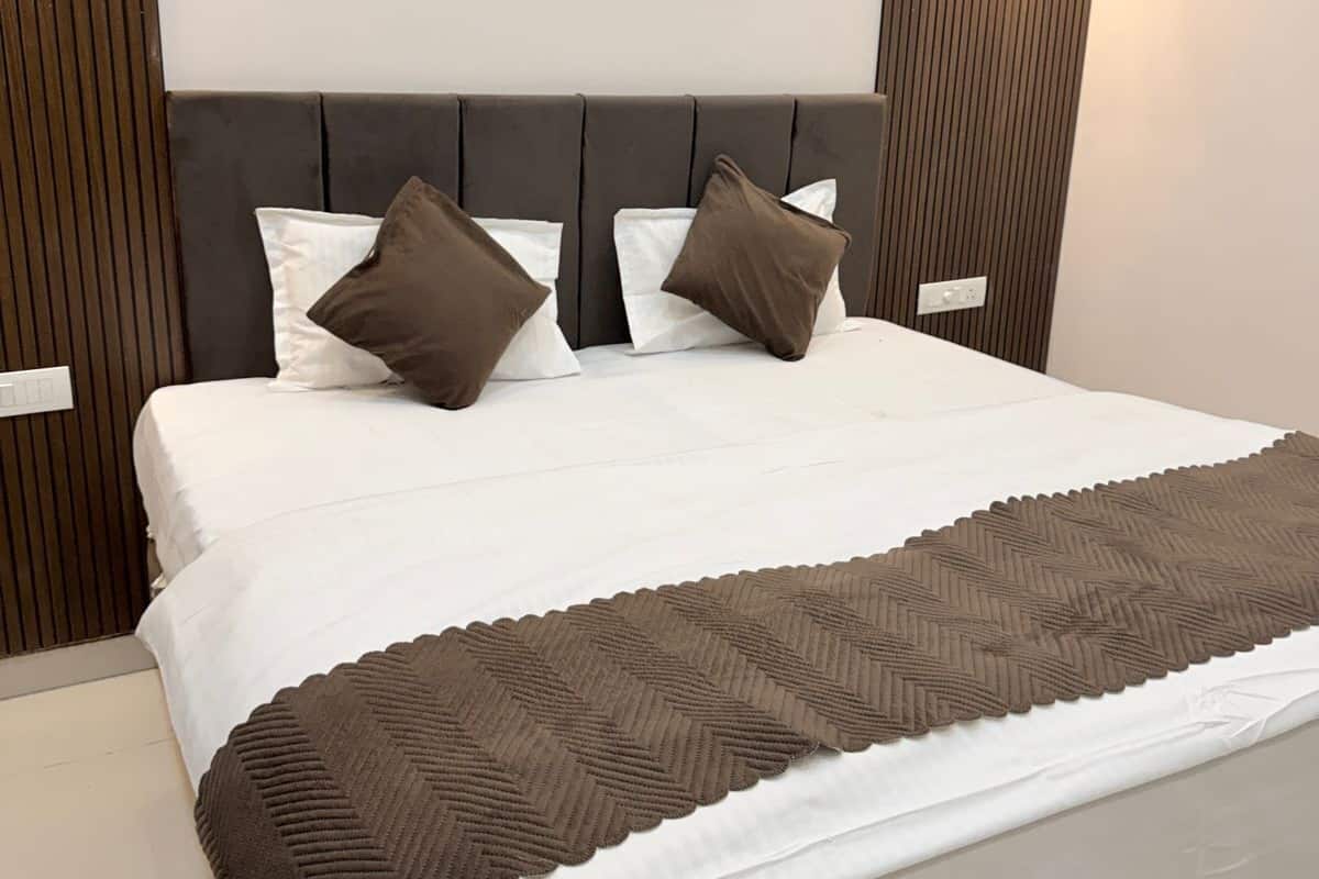 Ein Bett mit brauner Kopfteil, weißer Bettwäsche und einer braunen Decke.