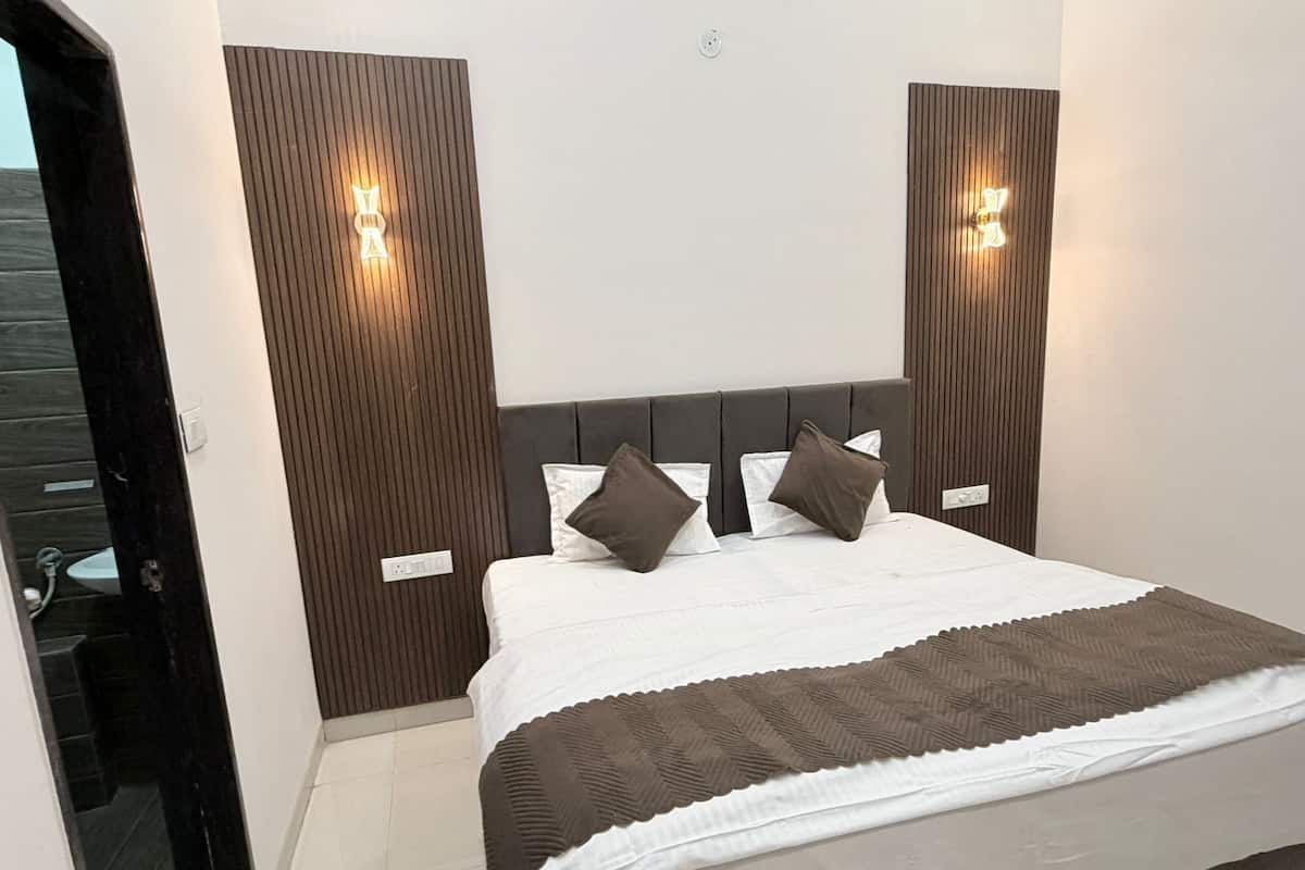 Ein modernes Hotelzimmer mit einem großen Bett, einem hölzernen Kopfteil und Wandleuchten.