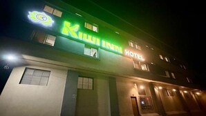 A hotel with a neon sign, a visible entrance, and a window with blinds. - Kiwi Inn Hotel Palda (Indore)