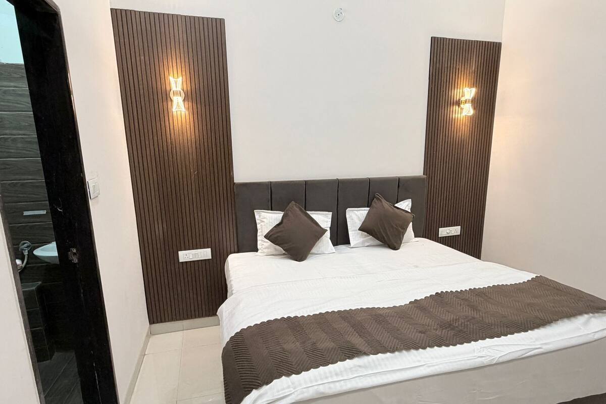 Ein Schlafzimmer mit einem Bett, Kissen, einem Kopfteil und Wandleuchten.