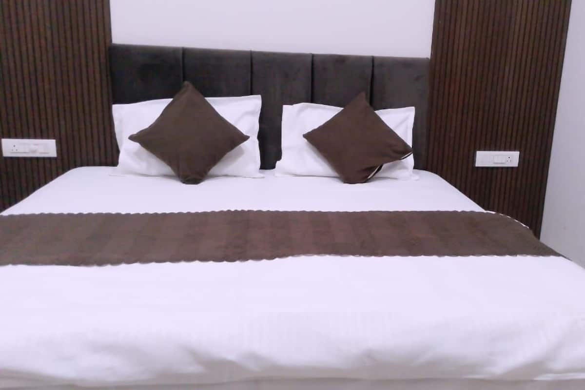 Ein Bett mit dunklem Kopfteil, weißer Bettwäsche und zwei braunen Kissen.