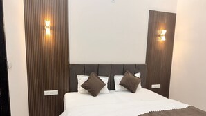 A hotel room with a bed, two wall-mounted lights, and a wooden panel design on the walls. - Kiwi Inn Hotel Palda (Indore)