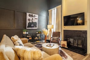 Una sala de estar con un sofá, chimenea, televisor y estantería.
