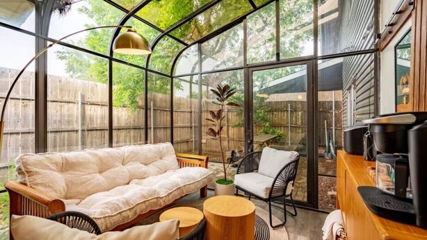 A cozy indoor space with a cushioned sofa, a chair, a small round table, and a coffee machine. - Sunlit Designer Home with Sunroom (Garland)