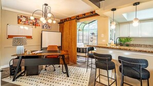 A modern kitchen with bar stools, a dining table, and a large window. - Sunlit Designer Home with Sunroom (Garland)