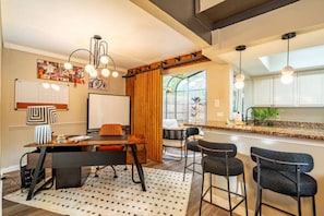 Una cocina moderna con taburetes de bar, una mesa de comedor y un ventanal grande.
