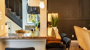 A kitchen with a granite countertop, a hanging light fixture, a potted plant, and a chair. - Sunlit Designer Home with Sunroom (Garland)