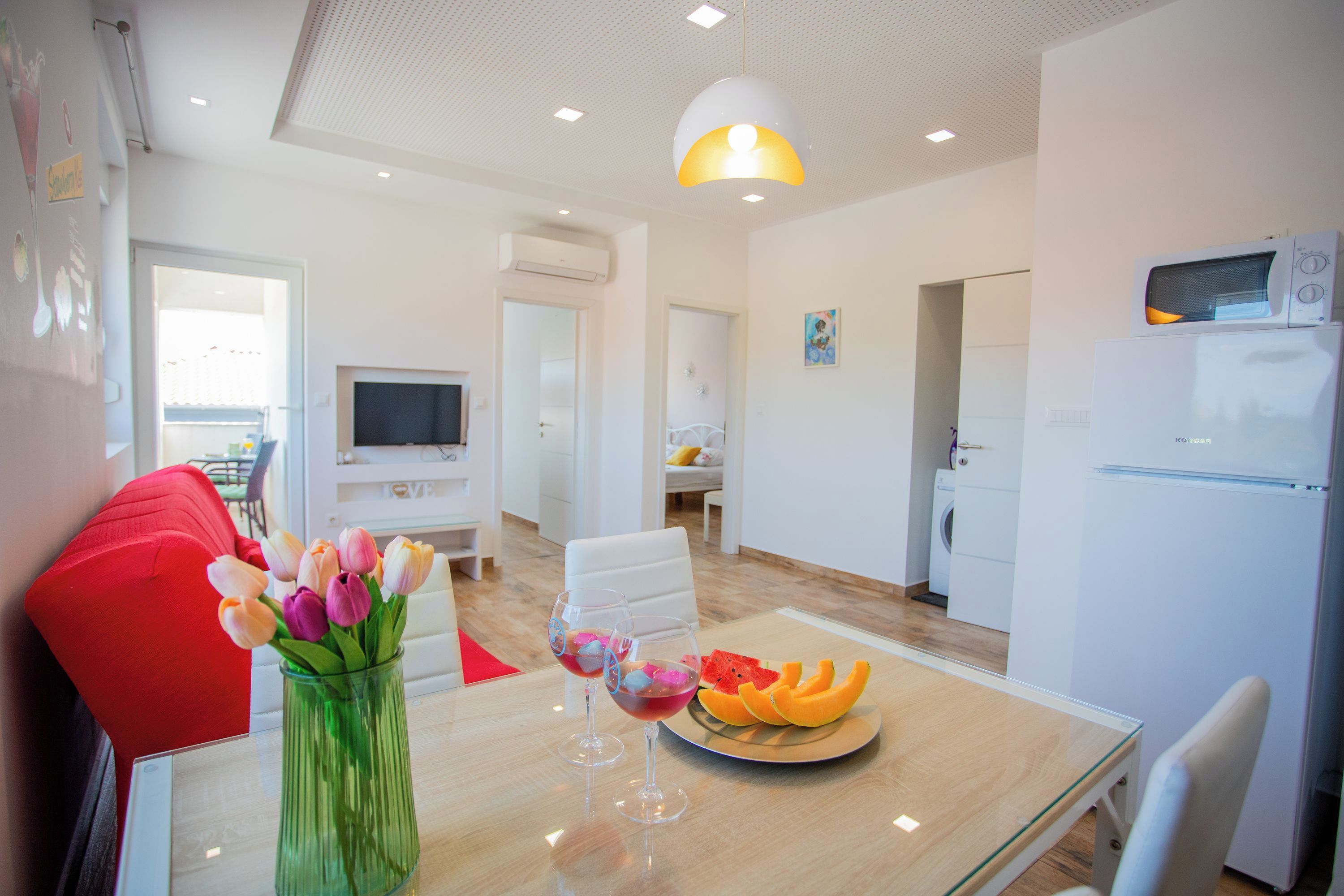 A modern kitchen with a microwave, refrigerator, and a dining area with a table, chairs, and a vase of flowers.