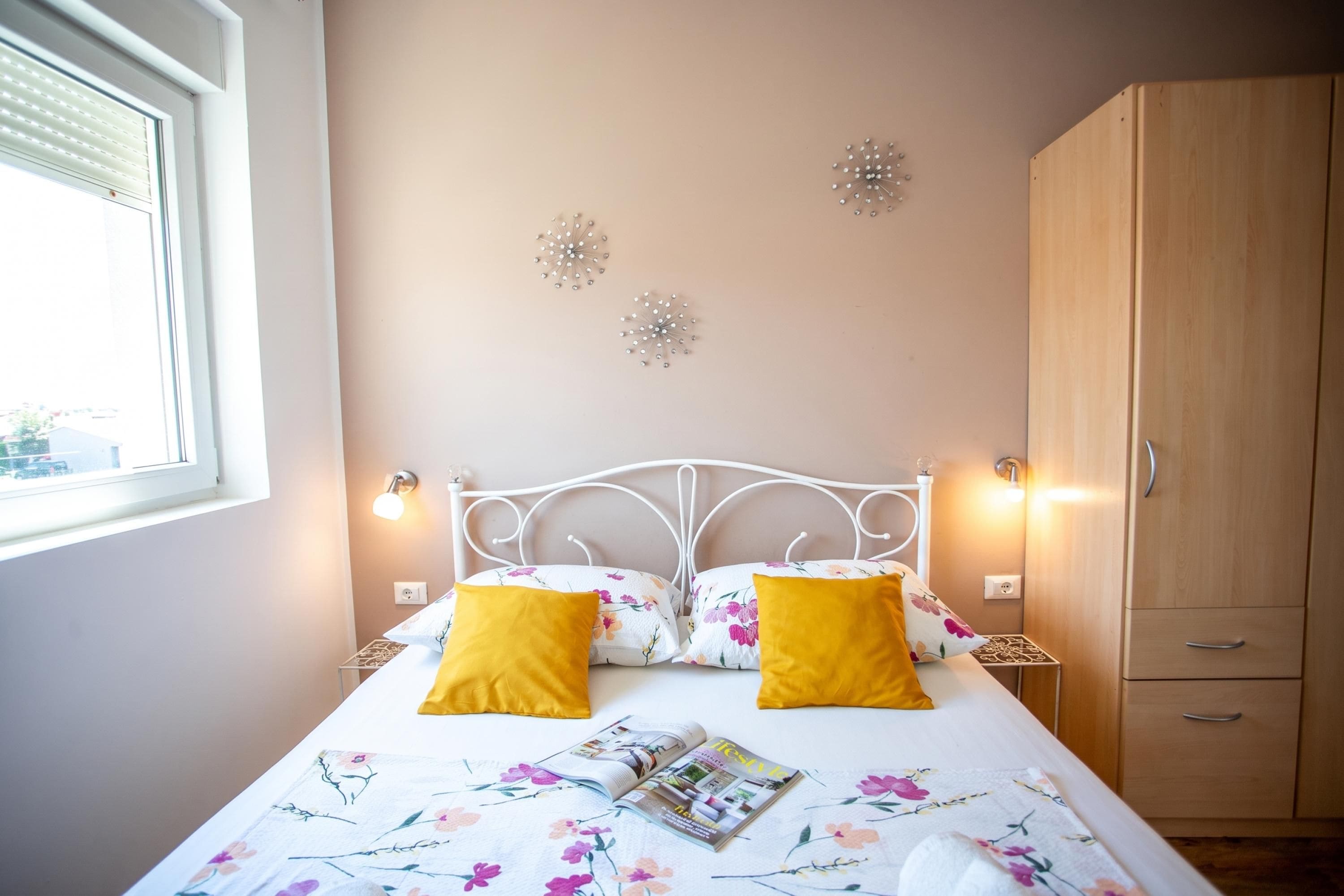 A bedroom with a bed, two bedside lamps, a wardrobe, and decorative wall art.
