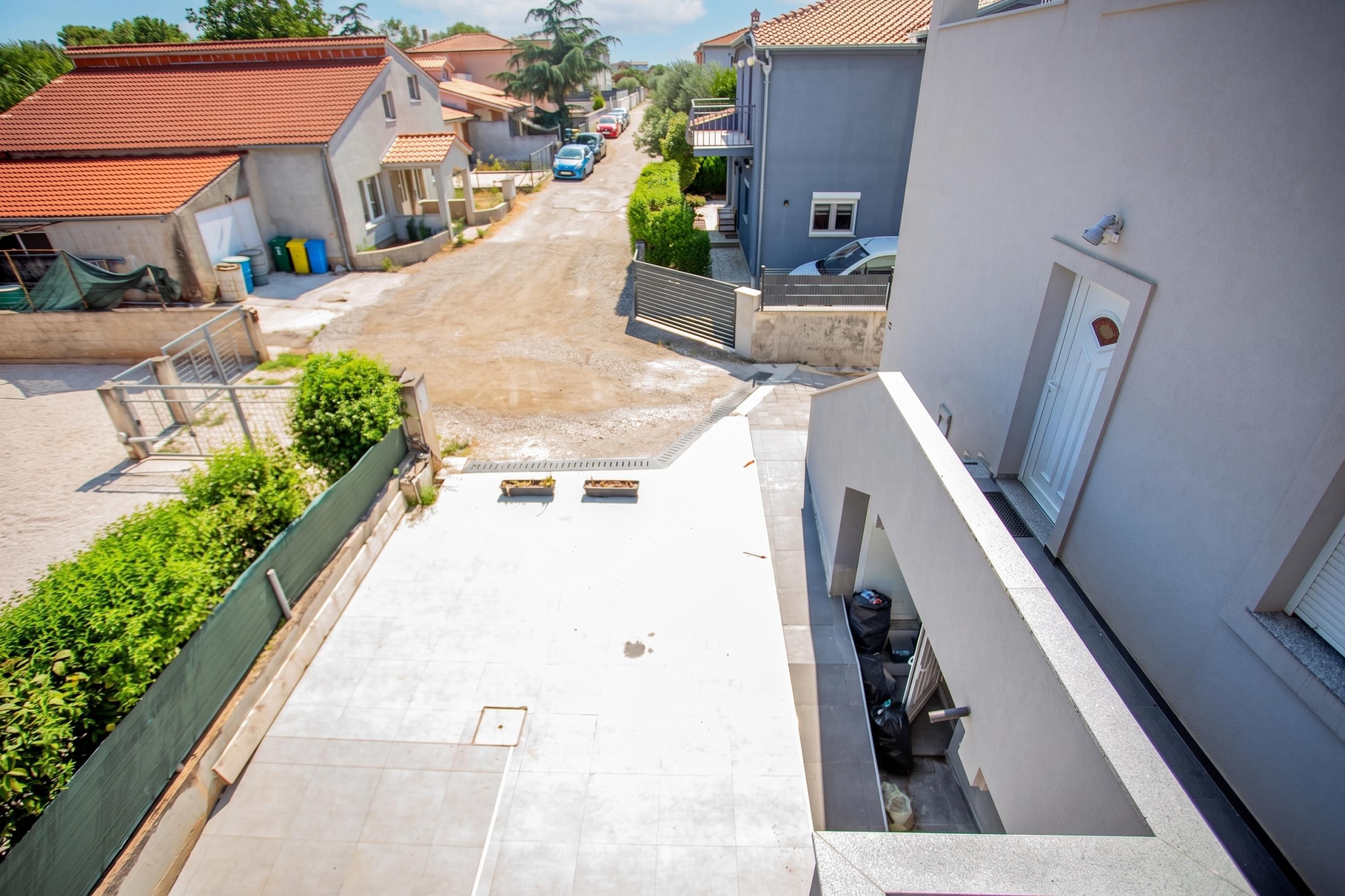 Rua residencial com casas, céu claro e rua asfaltada.