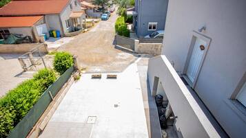 Rua residencial com casas, céu claro e rua asfaltada.