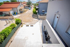 Rua residencial com casas, céu claro e rua asfaltada.