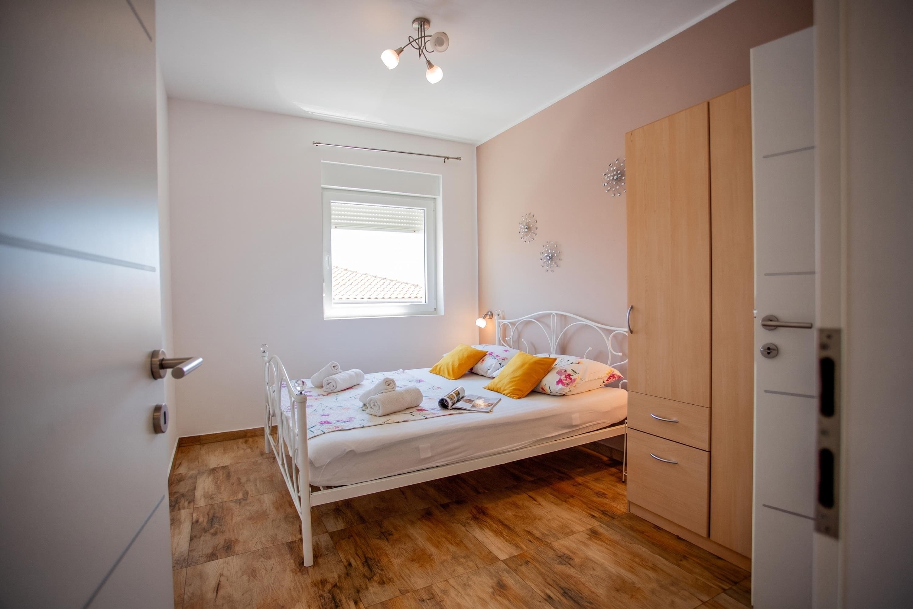 Une chambre à coucher avec un lit, une armoire, une fenêtre et un luminaire au plafond.