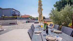 An outdoor dining area with a table set for four, surrounded by wicker chairs. - Sun And Fun (Pula)