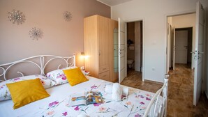 A bedroom with a bed, a wardrobe, and a bathroom visible through an open door. - Sun And Fun (Pula)