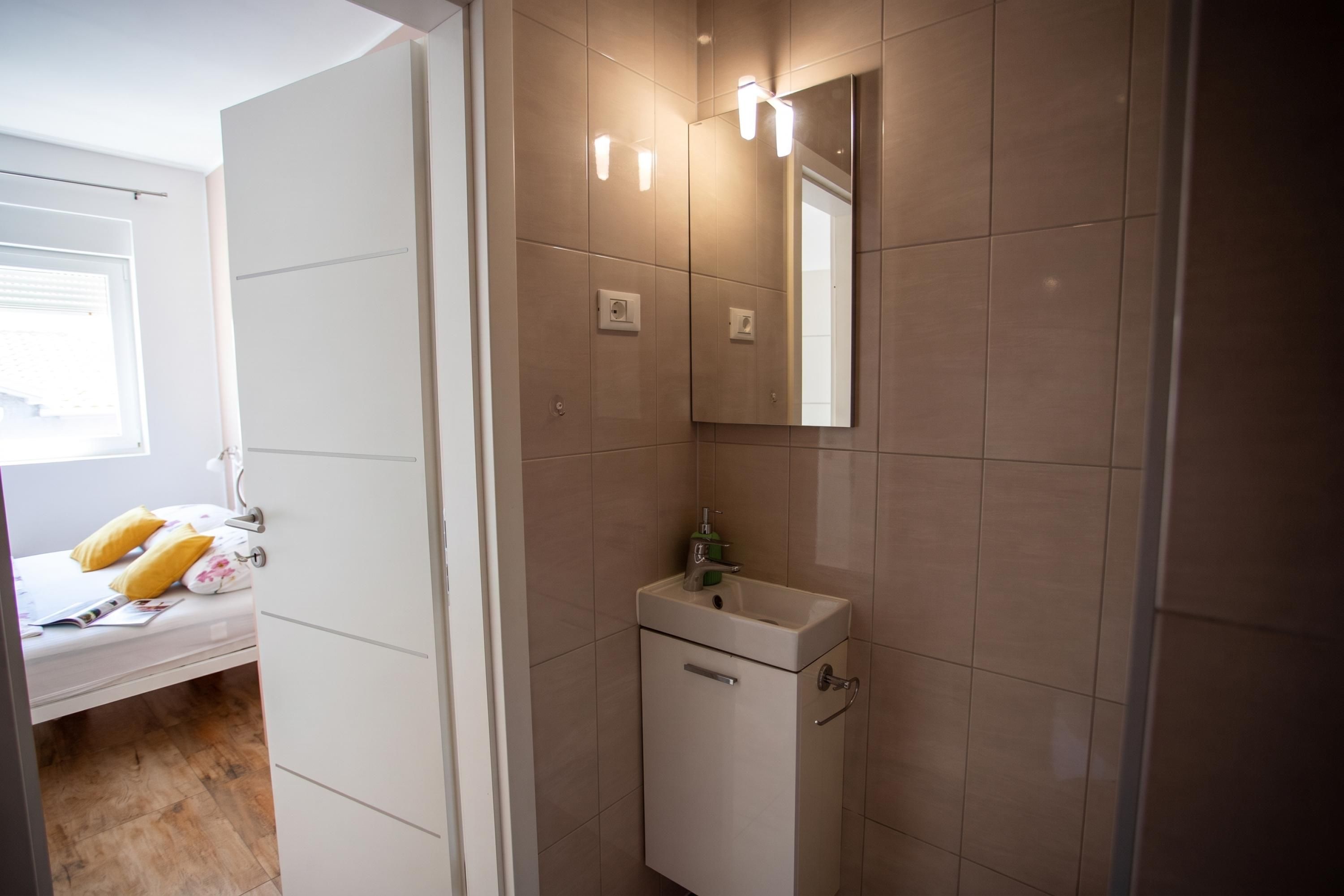 A bathroom with a mirror, sink, and light fixtures.
