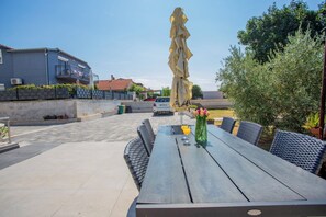 An outdoor seating area with a table and chairs, a statue, and a car parked in the background. - Sun And Fun (Pula)