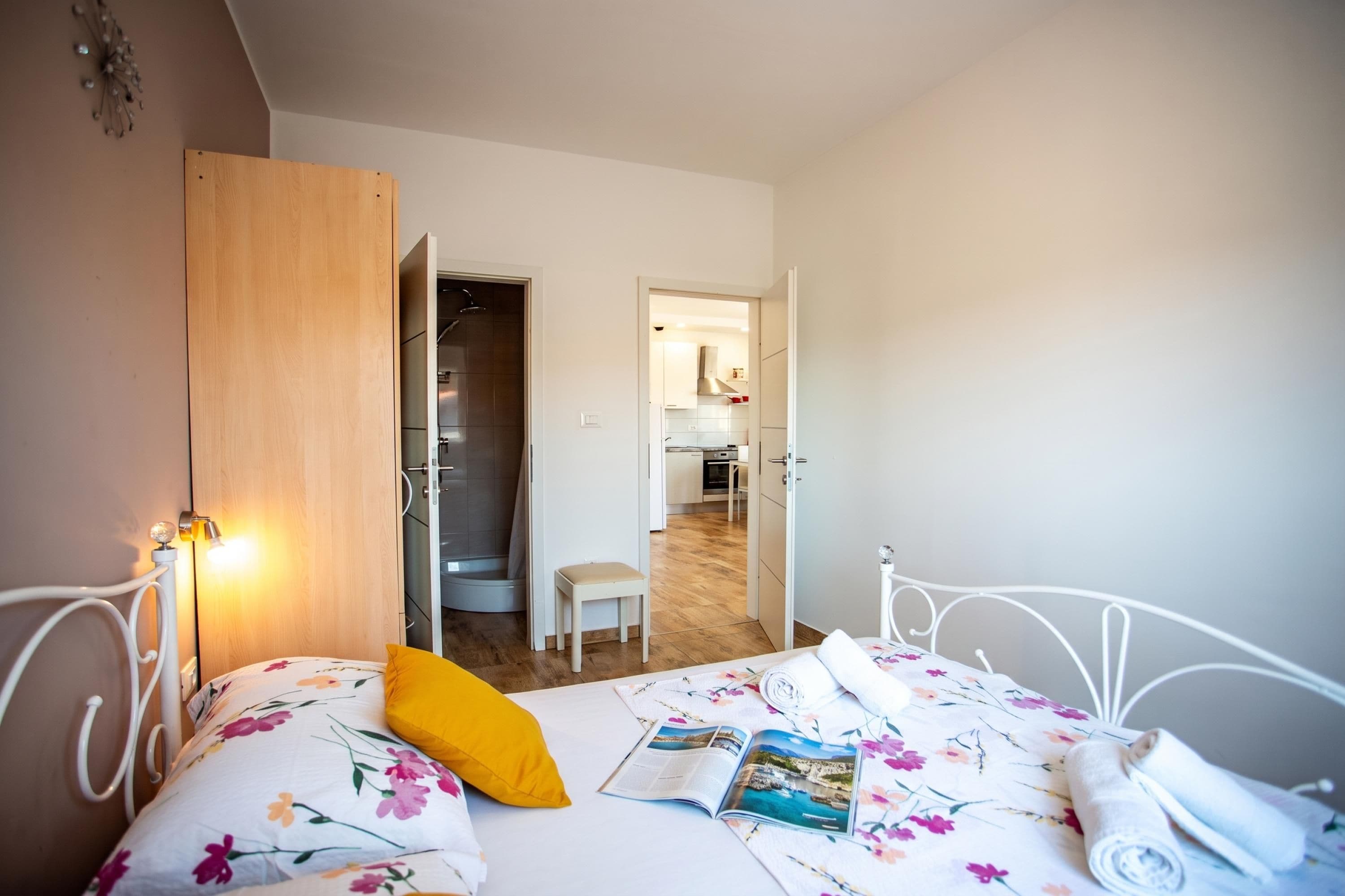 A bedroom with a bed, a bedside table, a chair, and a view into the adjacent bathroom.