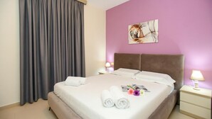 A hotel room with a bed, curtains, a nightstand, a lamp, and a wall art piece. - 203 B, One Bedroom Apartment (Vlorë)