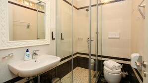 A bathroom with a glass-enclosed shower, a sink, a toilet, and a mirror. - 203 B, One Bedroom Apartment (Vlorë)