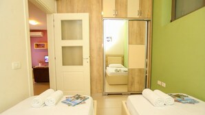 A hotel room with two beds, a mirror, a wardrobe, and a door leading to a bathroom. - 307a, Diamond Two Bedroom Apartment (Vlorë)