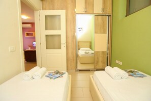 Ein Hotelzimmer mit zwei Betten, einem Spiegel, einem Kleiderschrank und einer Tür zu einem Badezimmer.