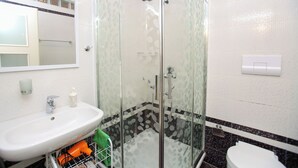 A bathroom with a glass-enclosed shower, a sink, a toilet, and a mirror. - 307a, Diamond Two Bedroom Apartment (Vlorë)