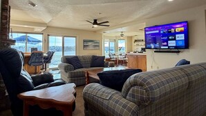 A living room with a flat-screen TV, a ceiling fan, and a view of the outdoors. - Lakeside Paradise - Hot Tub, Dock, 5bdrm, Firepit (Victorville)
