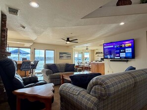 A living room with a flat-screen TV, a ceiling fan, and a view of the outdoors. - Lakeside Paradise - Hot Tub, Dock, 5bdrm, Firepit (Victorville)