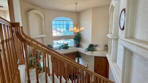 A grand staircase leading to a landing with a view of the outside. - Lakeside Paradise - Hot Tub, Dock, 5bdrm, Firepit (Victorville)